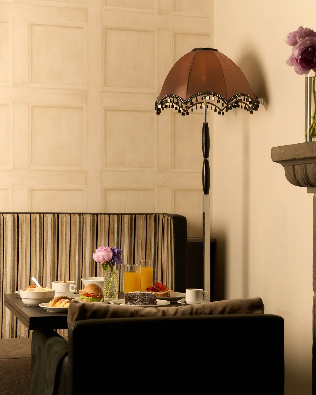 A breakfast table laid beneath a fringed floor lamp