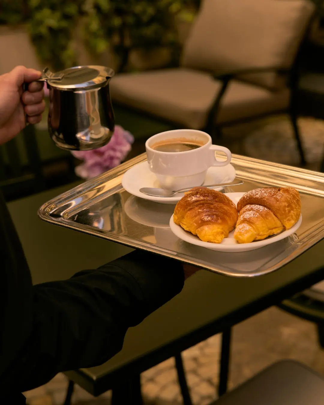 A tray of coffee and cornetti carried across the garden