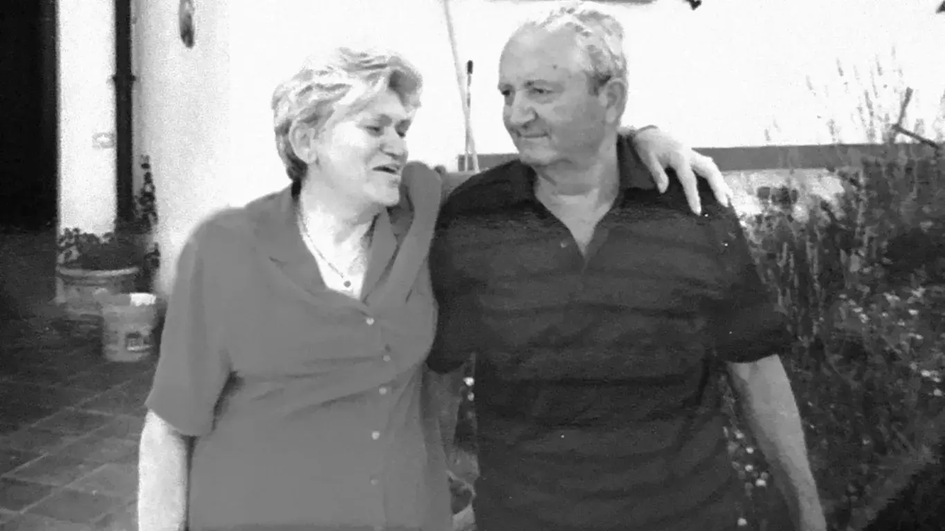 A black and white photograph of an older couple, arm in arm