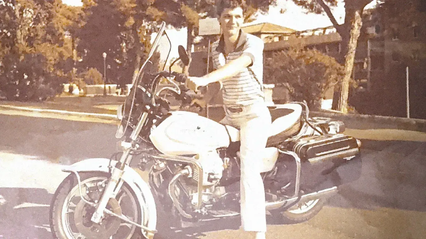An archival photograph of a young man sitting on a motorcycle