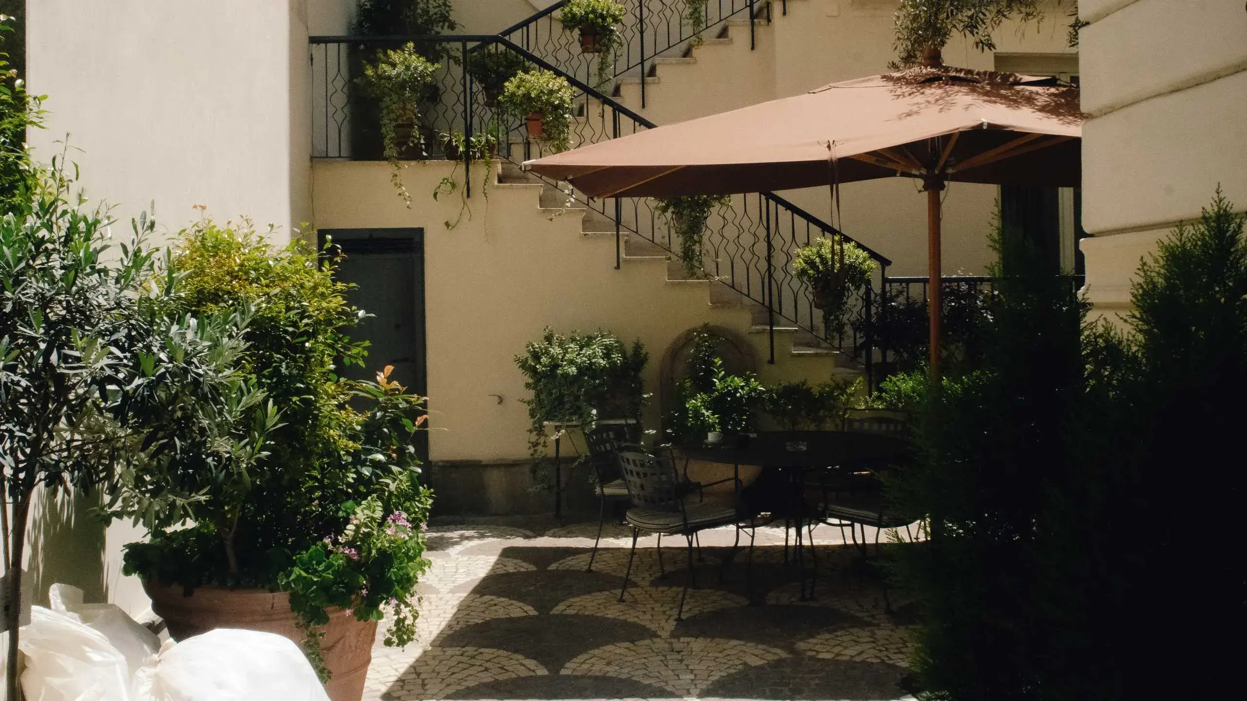 Royal Court’s quiet garden, with tables beneath a broad parasol and plants climbing the courtyard stairs