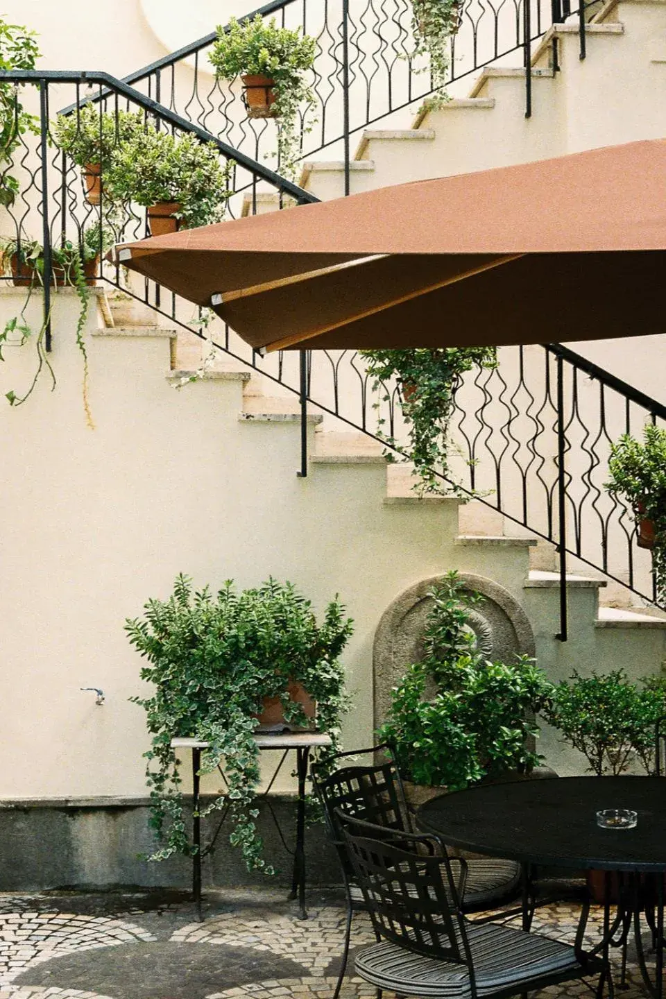 The garden staircase above a stone fountain, ivy on the rail