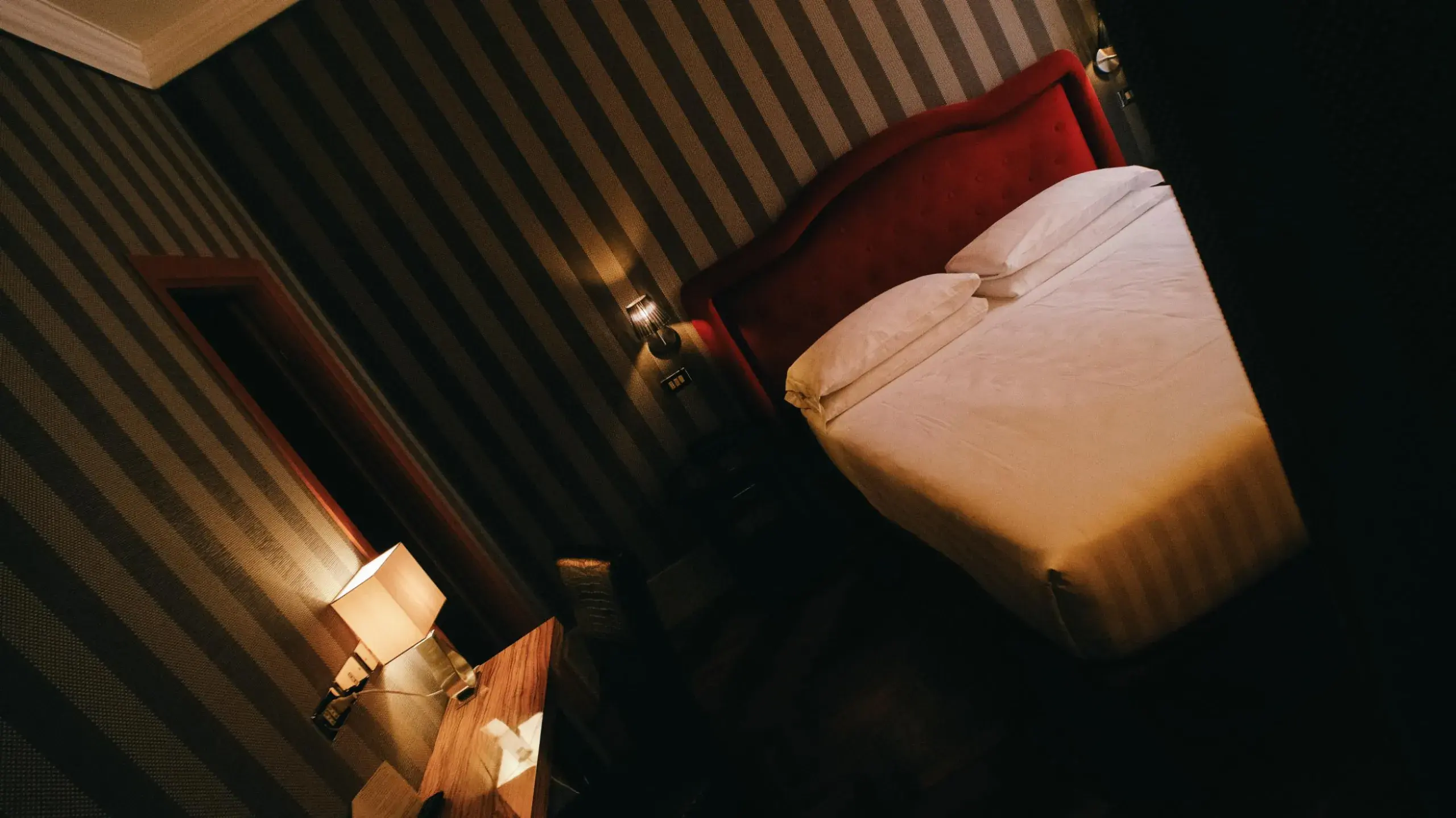 A room in the main hotel, red headboard against a striped wall
